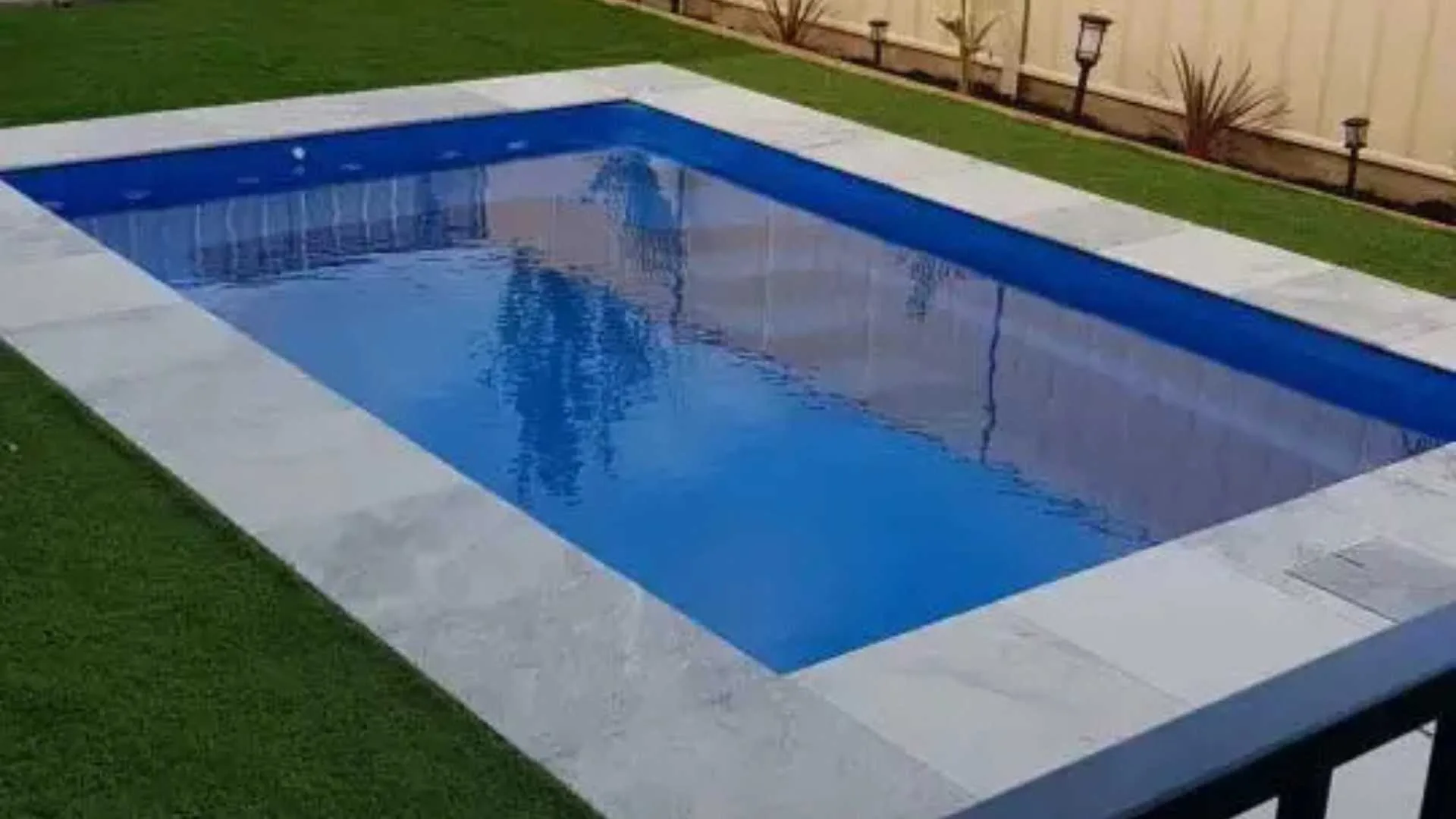 Rectangular backyard pool with stone border and lawn
