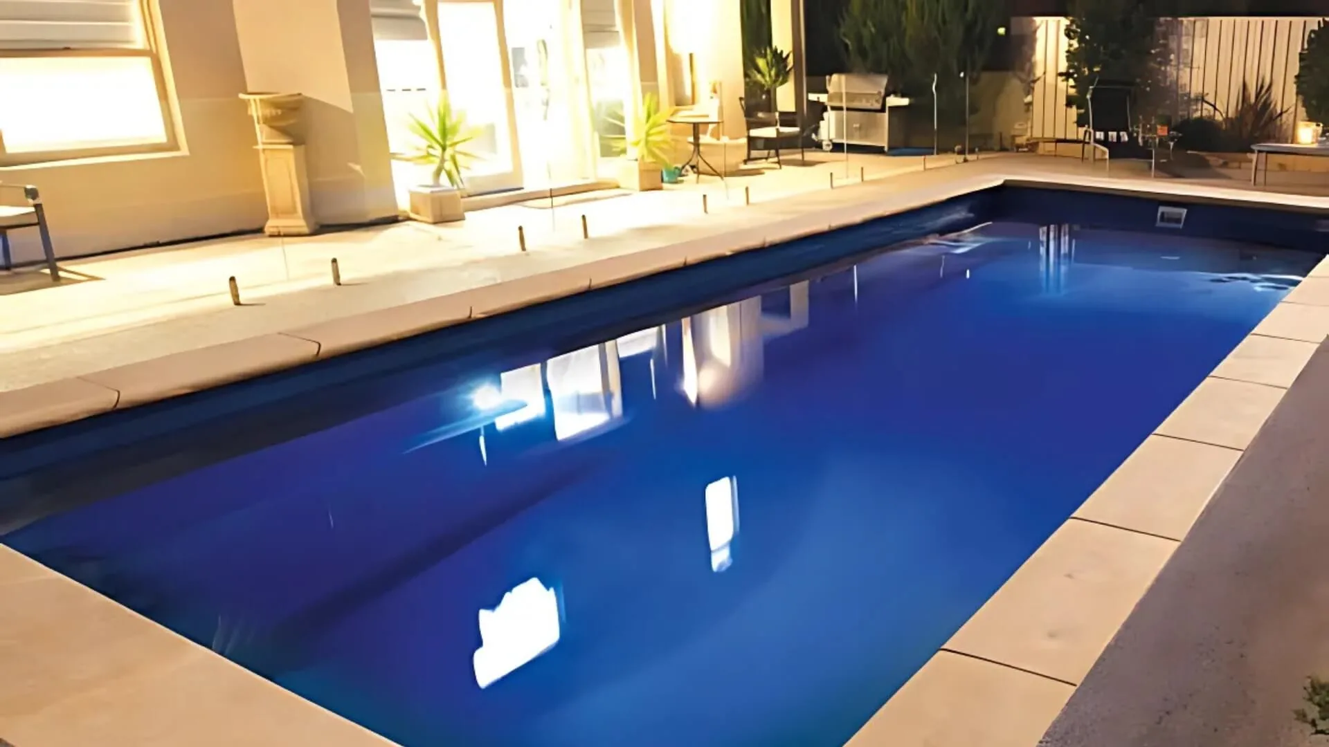 Night view of illuminated backyard swimming pool