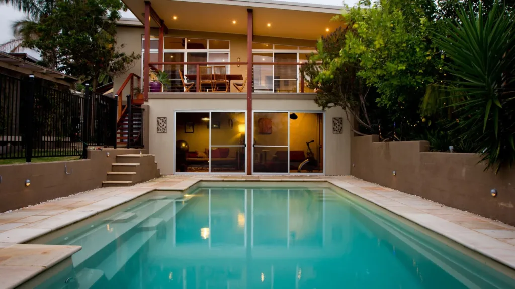 Two-story home with pool and lit patio at dusk view