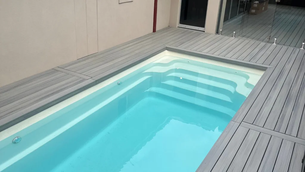 Compact backyard pool with deck and built-in entry steps