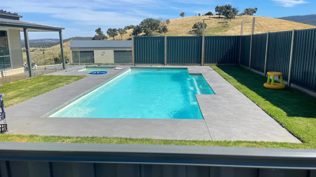Modern backyard pool with concrete deck and hill view