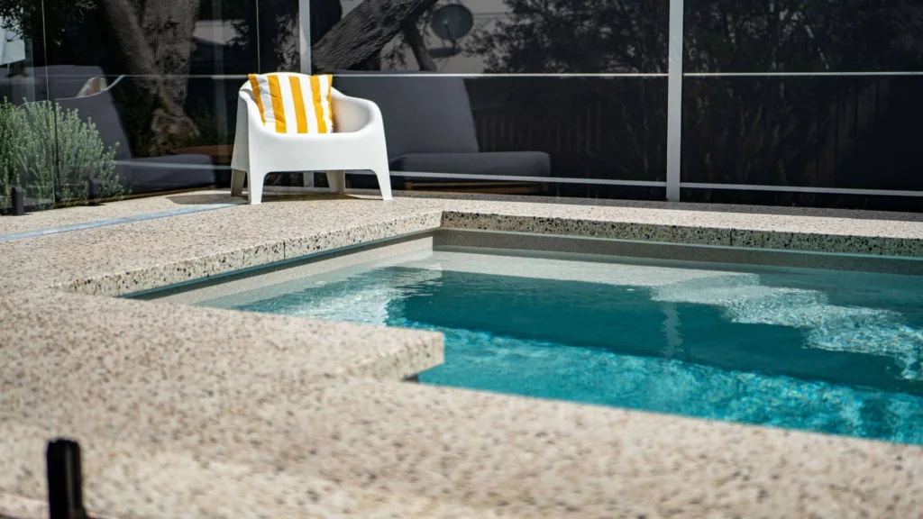 Small spa pool with textured deck and white chair setup