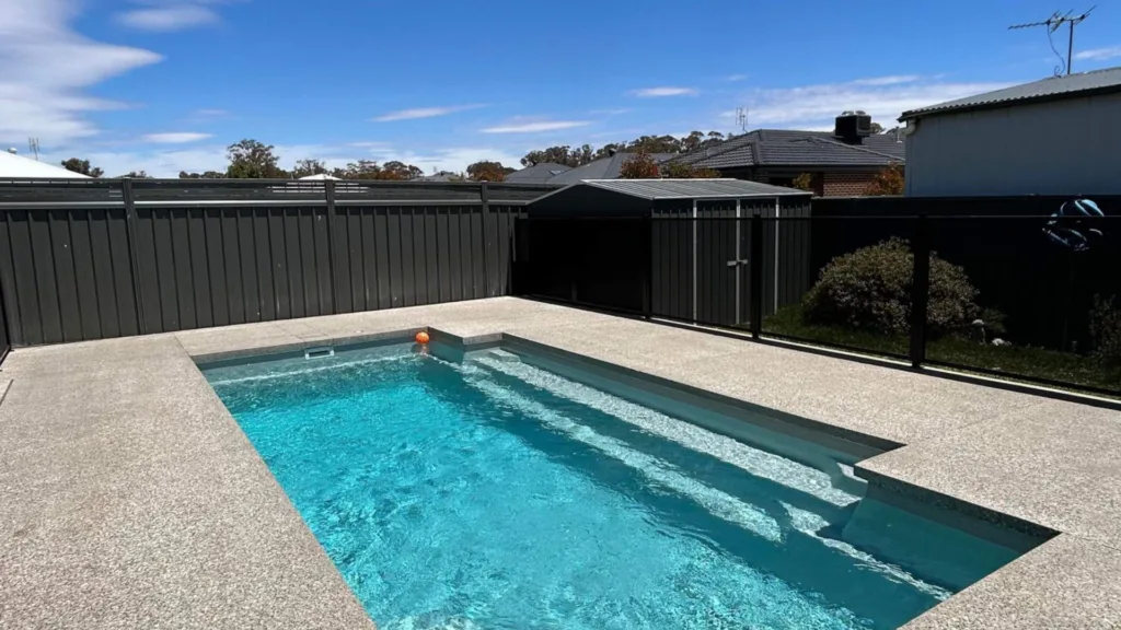 Modern backyard pool with fencing and clear blue water