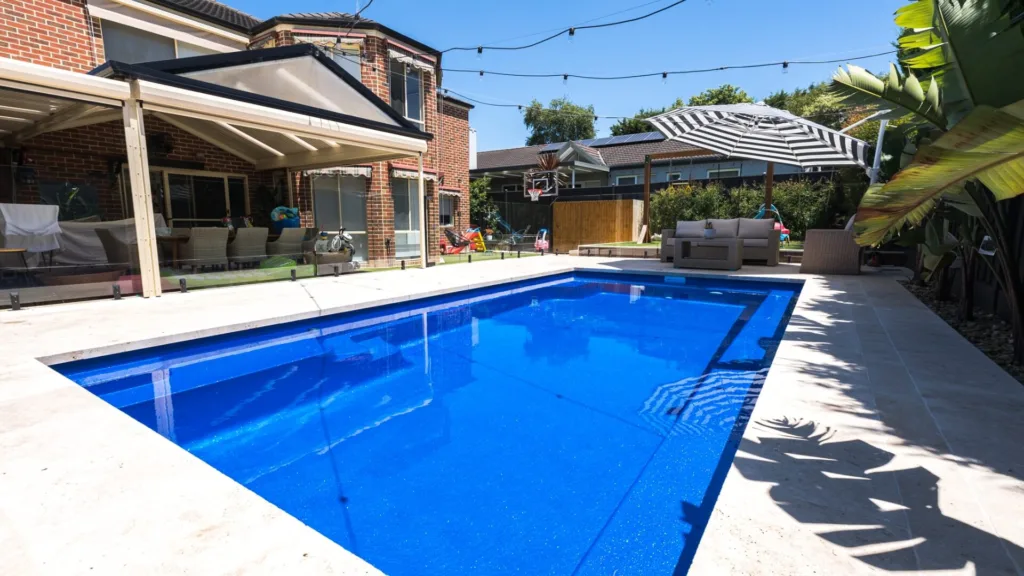 Modern backyard swimming pool with patio seating area