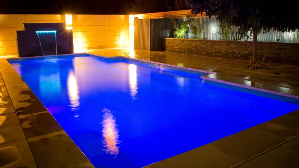Outdoor pool with lounge chairs and garden view in daylight
