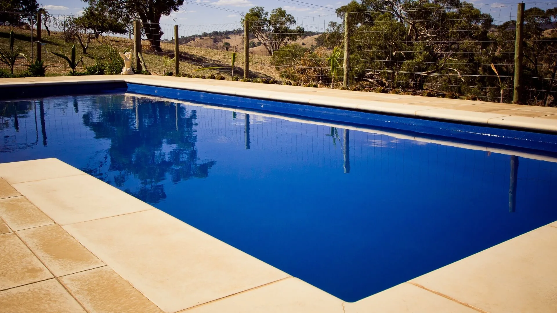 Large blue pool overlooking rural landscape and trees
