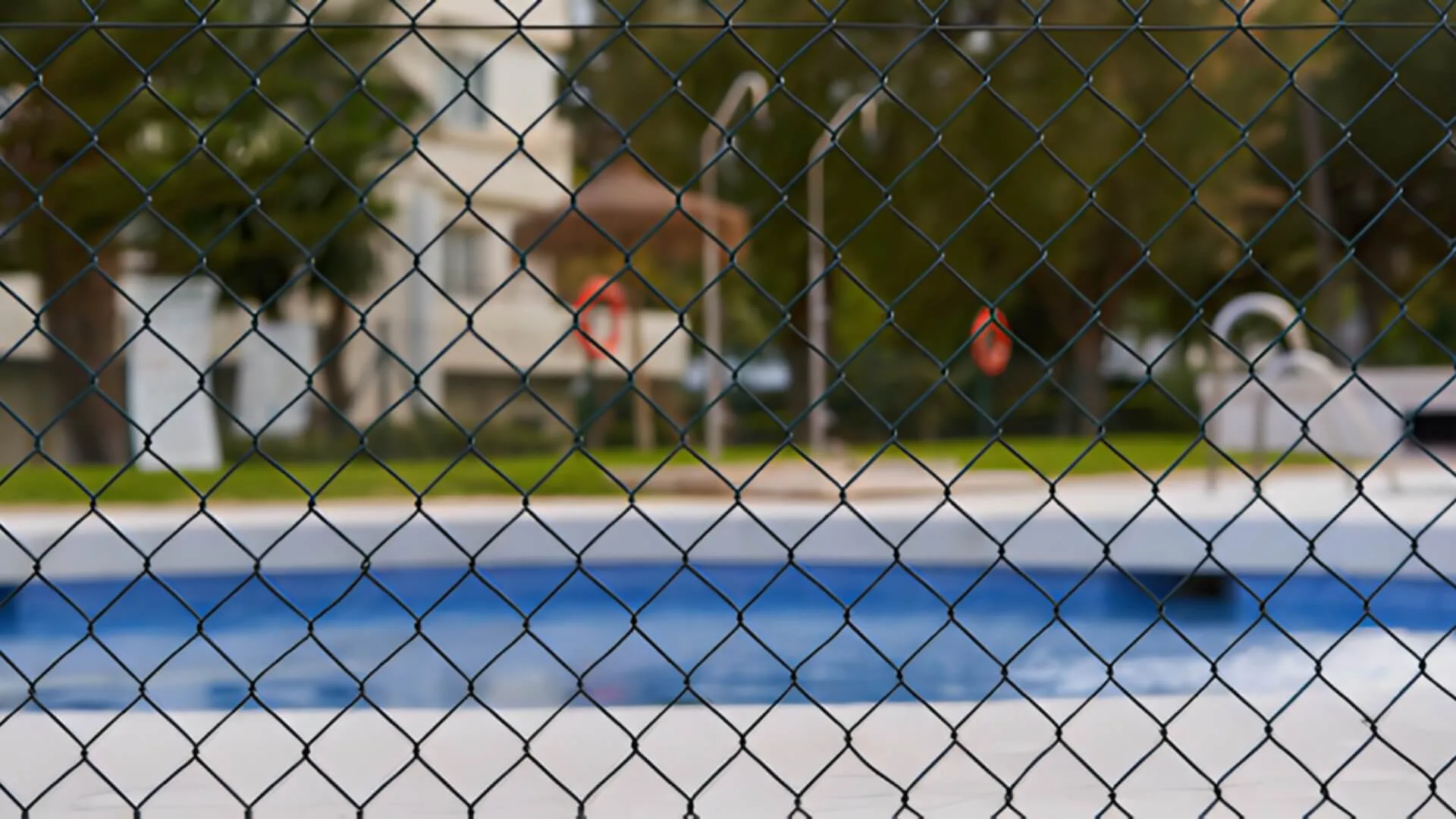 Swimming pool seen through chain link fence in backyard