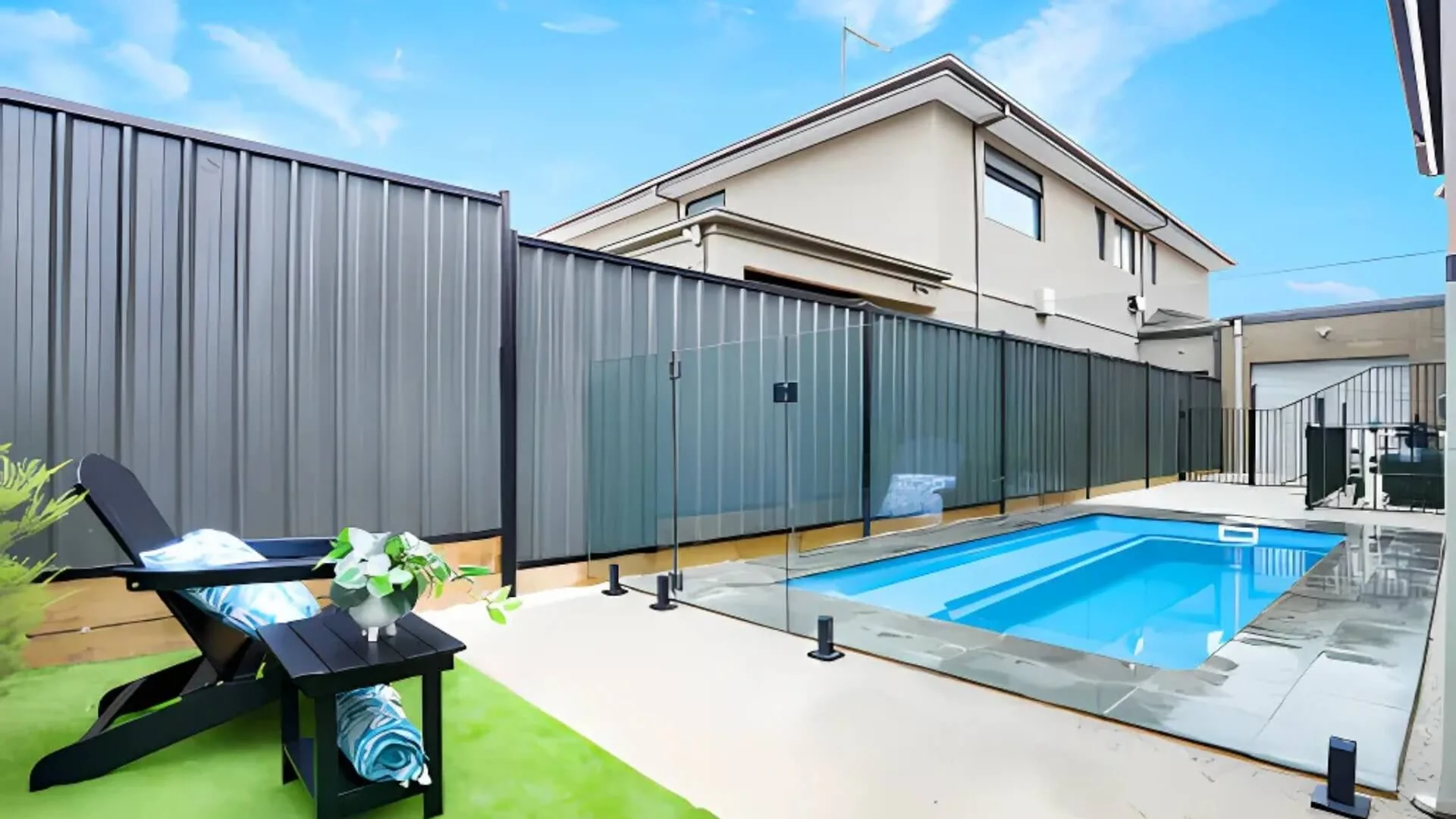 Modern backyard pool with glass fence and lounge chair
